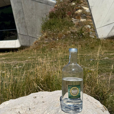 A labelled glass water bottle on a boulder in front of a curved concrete mountain museum