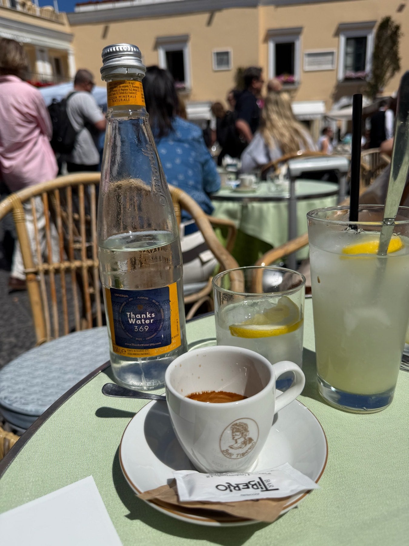 A labelled bottle beside an espresso cup at a café table