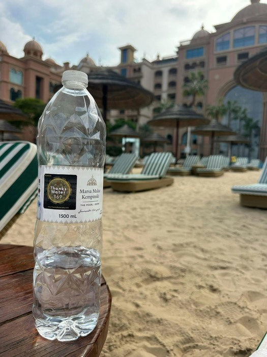 A labelled bottle on a sun lounger by a pool