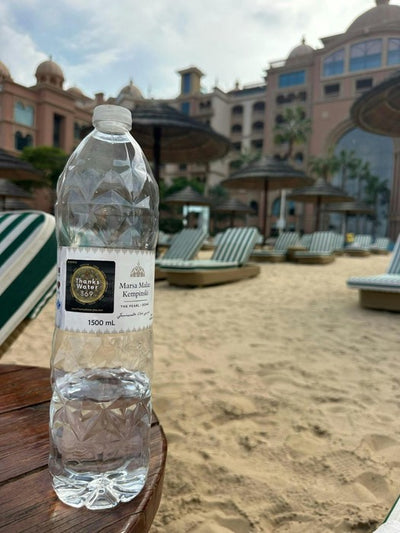 A labelled bottle on a sun lounger by a pool