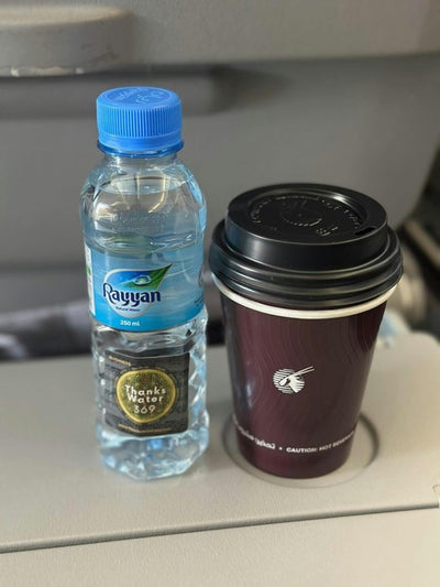 A labelled bottle beside a takeaway coffee cup